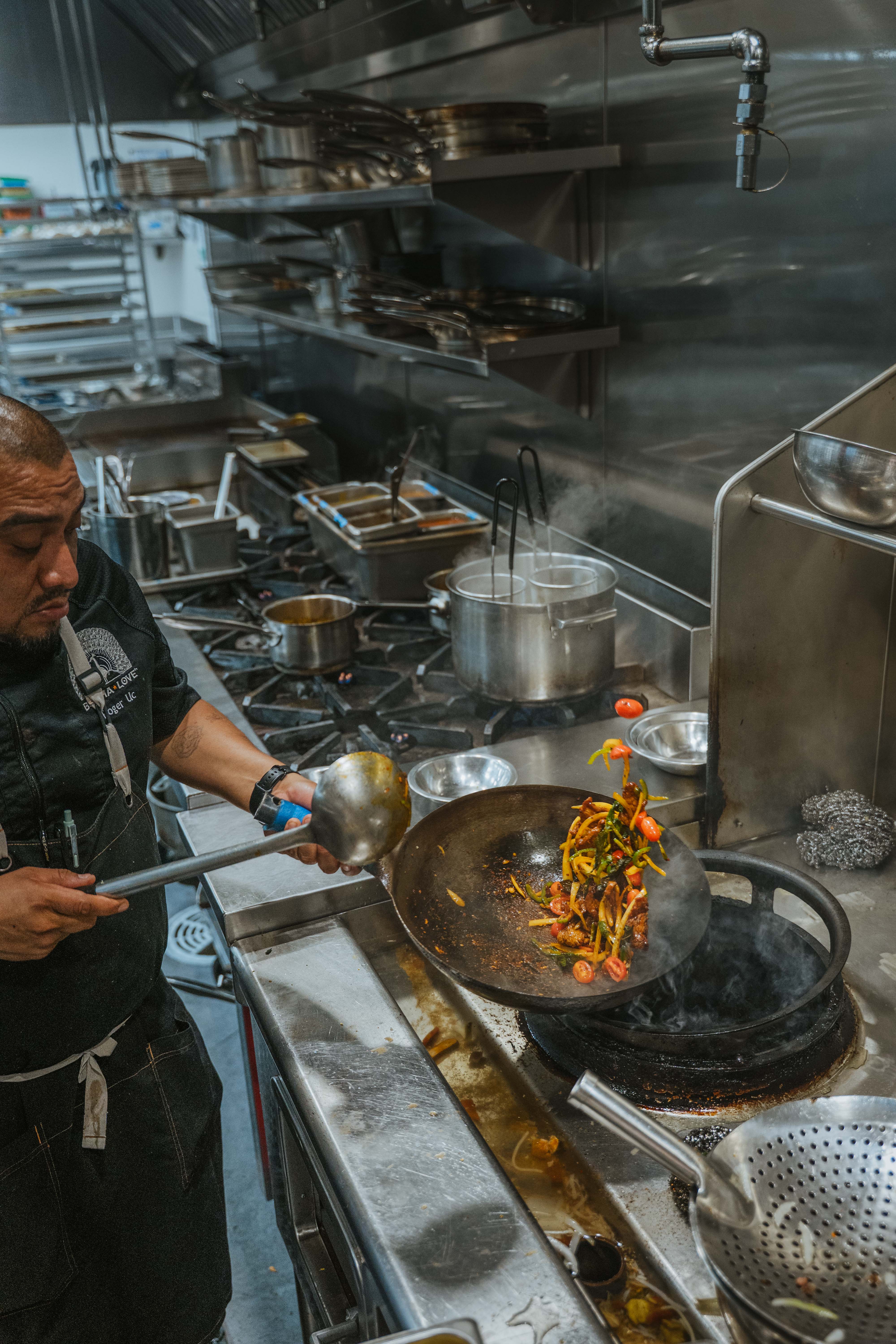 A Burma Superstar chef tossing a wok of Burmese stir-fry